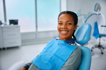 Happy black woman at dentist's office looking at camera.