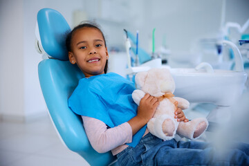 Happy black little girl at dentist's office looking at camera.