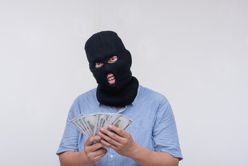 An middle aged thief in a black mask counting his robbed money. A robber Isolated on a white...