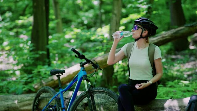 Cyclist in helmet drinks water from bottle after bike ride	