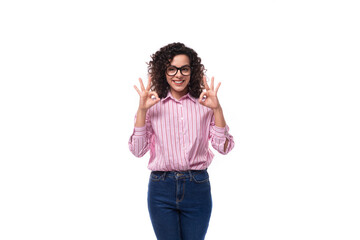 young european curly brunette lady in a pink blouse works in the office on the background with copy...