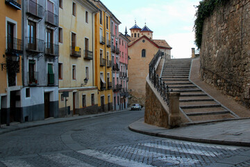 Photo of a street view of the historic center of Cuenca with colorful houses, stairs and a church...