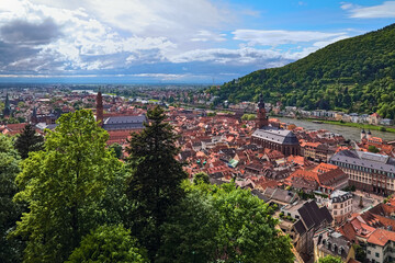 Heidelberg, Germany. High angle view over the Old Town and Neckar river from the lower slope of Konigstuhl hill. A cloud front is approaching from the Upper Rhine Plain.