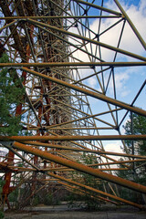 The photo captures an elaborate metal construction amidst sparse vegetation under a cloudy blue...