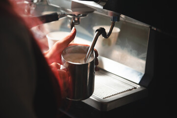 Making cappuccino on a professional coffee machine. The process of frothing milk.