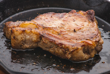 Grilled pork steak in frying pan on black background with copy space. Top view, flat lay food