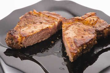 Grilled pork steak in frying pan on black background with copy space. Top view, flat lay food