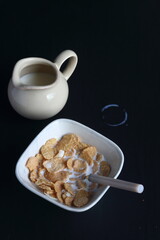 Bowl of cereal, cornflakes with milk in a bowl on a black background
