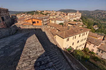 Fototapeta na wymiar Ancient Italian town on hill with tiled roofs of buildings, church and bell tower, Perugia, Italy