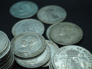 Silver 5 pesetas coins, duros, on a black background