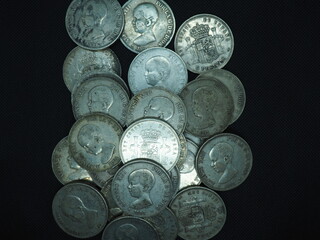 Silver 5 pesetas coins, duros, on a black background