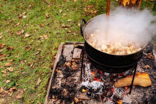 Preparation of delicious unhealthy fried pork greaves in a cauldron on the open fire. Delicious fried pork greaves in the pan traditional Romanian Christmas dish. Crispy deep fried