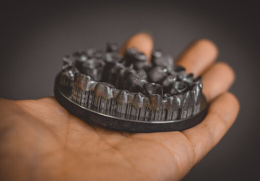 Man is holding object printed on metal 3d printer. Dental crowns created in laser sintering machine close-up. DMLS, SLM, SLS technology. 4.0 industrial revolution. Progressive modern additive technol
