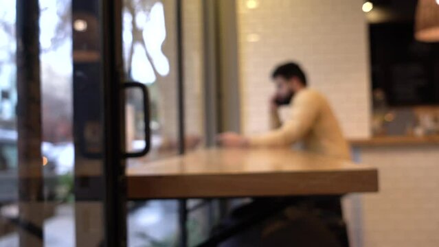 Blurry image of a man discussing on a phone call in a cafe. Copy space.