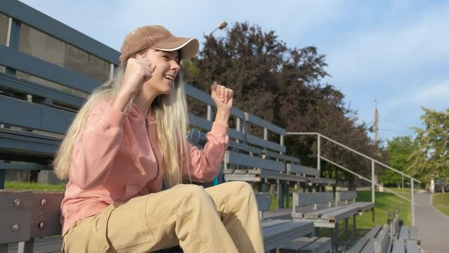 Teen enjoy sport game on stadium. A young sport girl enjoy the free time on tribunes during team playing in the sun.