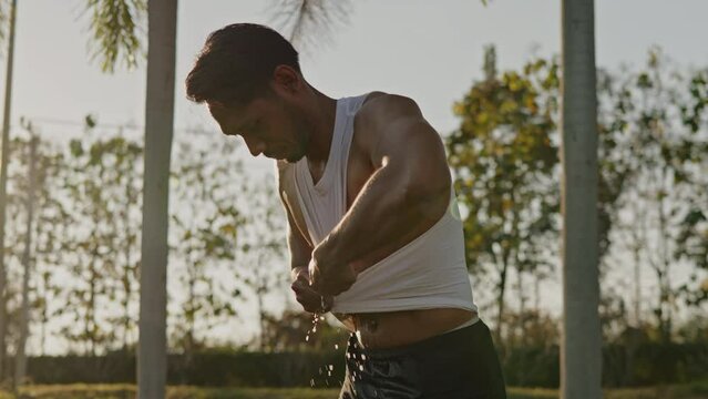Sport man is drinking water and cooldown after running in the park the washing face and head.