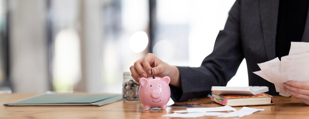 Businesswoman hand putting money coin into piggy for saving money wealth and financial concept.