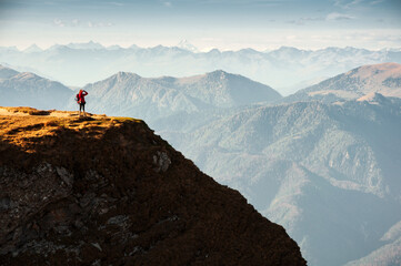 Tourist Hiker in red Jacket Standing on the Border of a Mountain Cliff Admiring the View