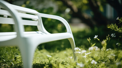 Cropped Close-up of empty white garden bench in garden in summer surrounded by blooming plants, greenery and flowers. Exterior of garden plot, background for furniture store. - obrazy, fototapety, plakaty