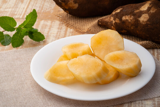 Close up peeled Yacon root fruit(Smallanthus sonchifolius) in white plate on wooden table.