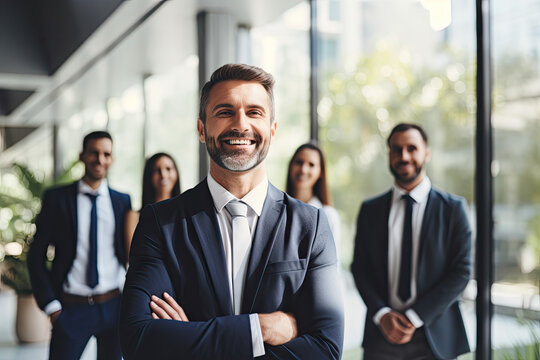 Portrait of confident mature businessman standing in front of his business team