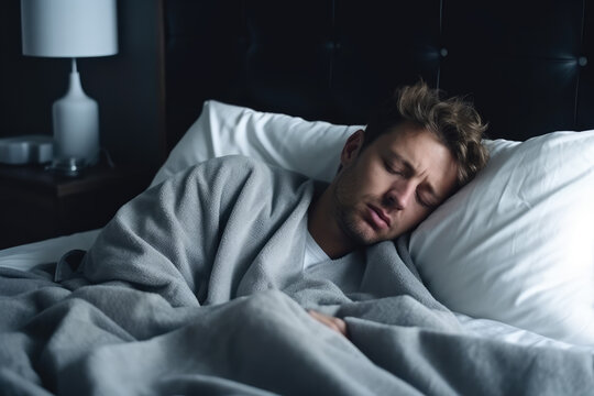 Sick man blowing his nose while lying in bed at home.