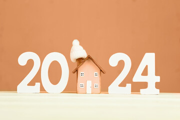 Happy New Year 2024 and Merry Christmas greeting card. Toy wooden house, white numbers 2024 on a...
