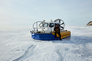 Hovercraft on transparent ice with cracks of frozen Lake Baikal. Khivus - transport on ice. Winter trip.
