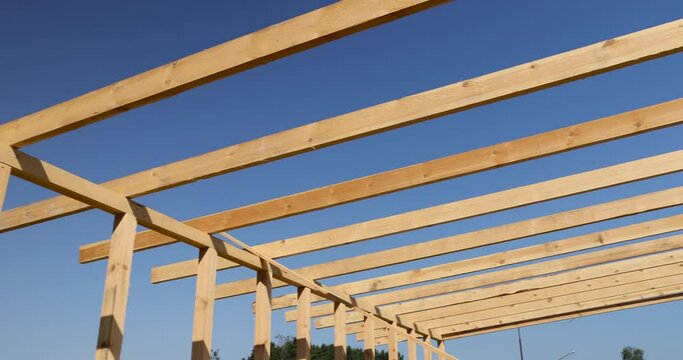 the wooden frame of the building against the blue sky, the construction of a new building, the frame of which is built of pine wood