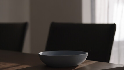 Single blue ceramic bowl on wood table in dark interior