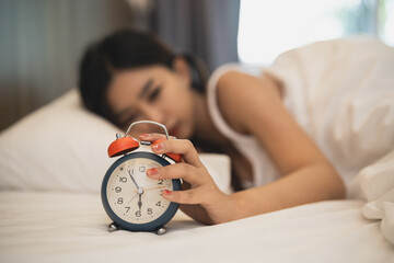 Close up alarm clock. woman sleeping in comfortable bed with silky linens in the morning. Women...