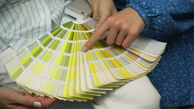 Two young female choosing paint color from palette for new interior design. Close up palette
