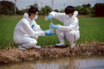 Factory scientists or biologists wear protective clothing while checking natural water sources, Chemical protection that may leak into natural water sources and Collecting water samples near farmland