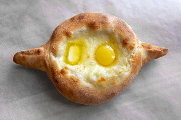 Adjara khachapuri - cheese pie with egg yolk and butter on parchment paper