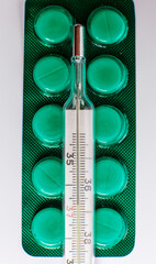 Different tablets for treatment and a thermometer for measuring body temperature, medicine