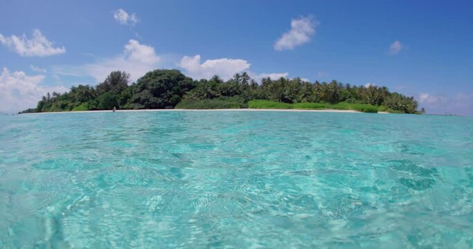 Half underwater transparent ocean and view with tropical island in Maldives