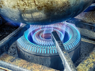 cauldron boiling over the blue flame of an industrial stove