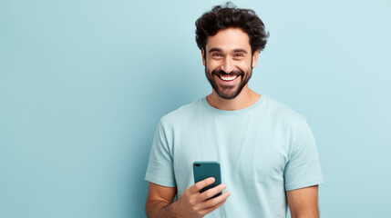 Young man smiling and holding his smartphone on a colored background - obrazy, fototapety, plakaty