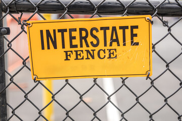 Yellow interstate fence sign with black words
