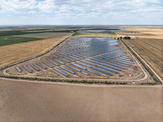 Fototapeta premium Aerial view of a large solar panel plant to create clean electrical energy in the middle of agricultural expanses