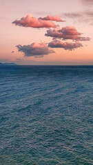 Pink clouds in evening sky over blue sea, twilight fabulous sunset, copy space, vertical frame