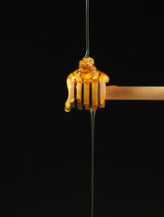 Yellow liquid honey dripping from the honey spoon