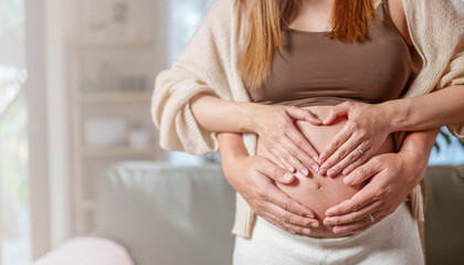 mother, family, maternity, pregnant, woman, pregnancy, baby, motherhood, love, happiness. close up of happy pregnant newbie mother with big belly and newbie father embrace to her belly near sofa. - obrazy, fototapety, plakaty