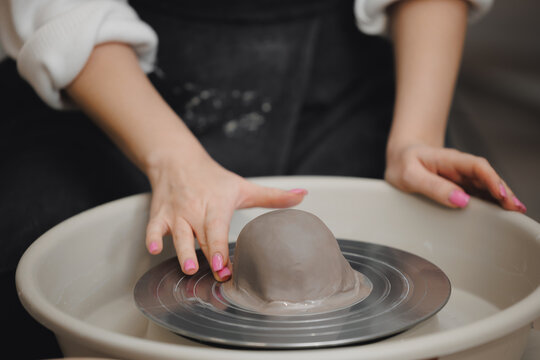 Hands young woman with manicure master on potter wheel makes clay dishes, relax DIY business.