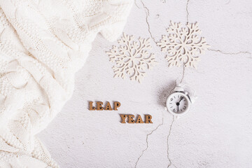 Leap year concept, calendar, alarm clock, sweater and snowflakes on a light top view