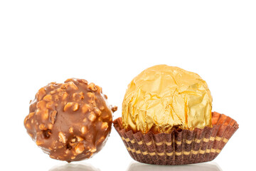 Two chocolate candies with a nut in a paper wrapper, macro, isolated on a white background.