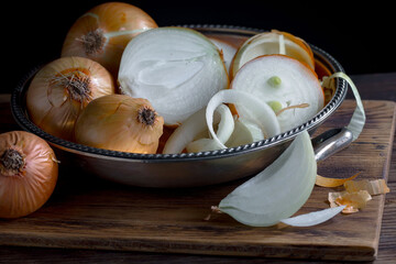 Ripe onion is a spicy product and vegetable. It is essential in the preparation of many delicious dishes. On an old background in a composition with kitchen accessories.