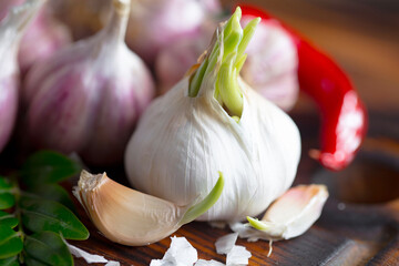 Garlic is a ripe, spicy product, a spice. It is essential in the preparation of many delicious dishes. On an old background in a composition with kitchen accessories.