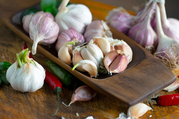 Garlic is a ripe, spicy product, a spice. It is essential in the preparation of many delicious dishes. On an old background in a composition with kitchen accessories.