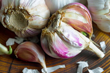 Garlic is a ripe, spicy product, a spice. It is essential in the preparation of many delicious dishes. On an old background in a composition with kitchen accessories.
